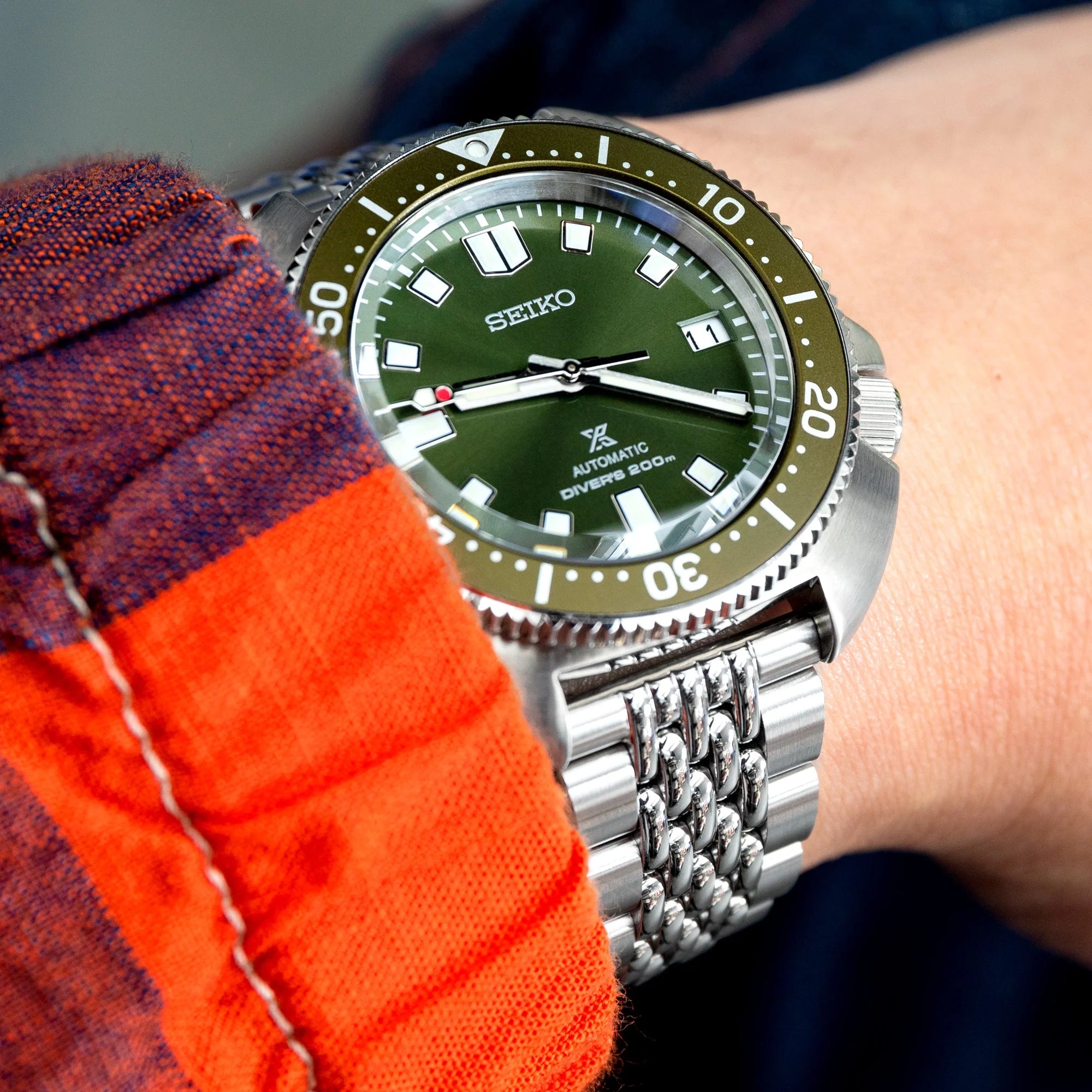 Seiko automatic diver watch with green dial and olive bezel on stainless steel Strapcode bracelet worn on wrist