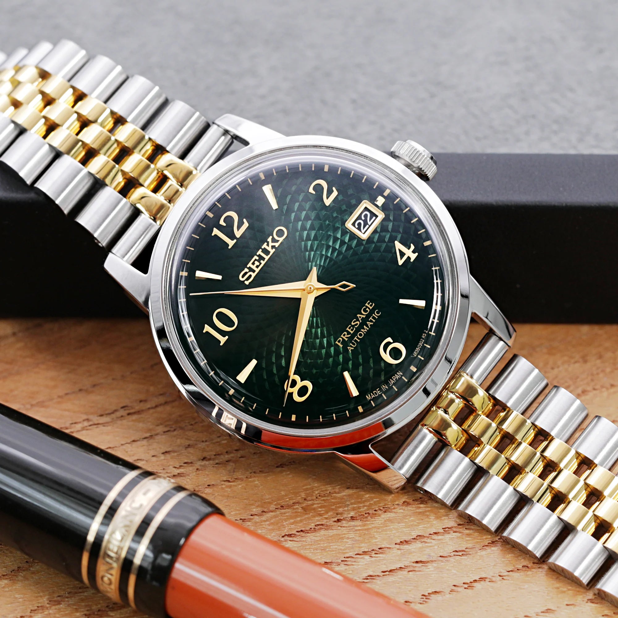 Seiko Presage automatic watch with dark green dial and two-tone steel gold bracelet on wooden surface