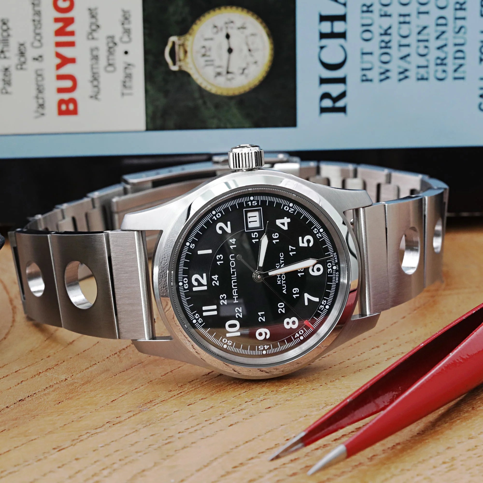 Stainless steel watch bracelet with quick release rollball mechanism and diver's deployant clasp on wooden surface