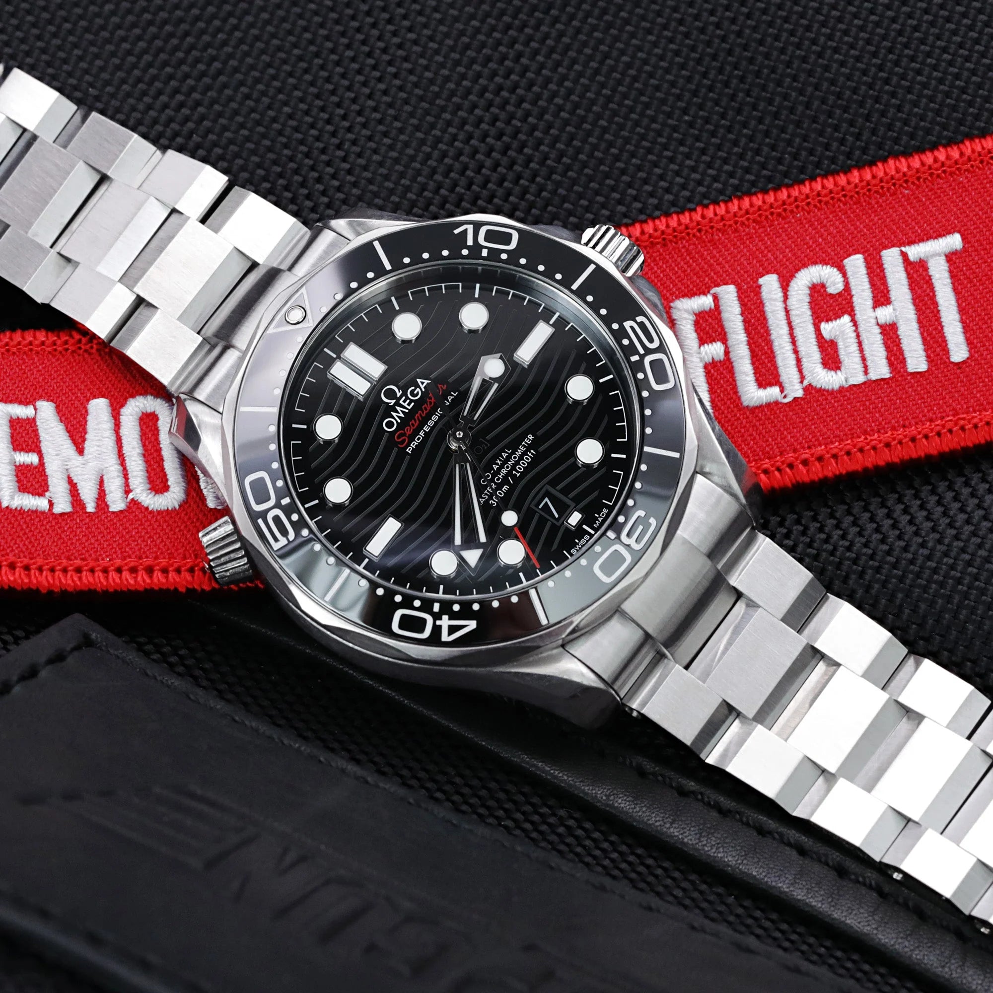 Omega Seamaster 42mm dive watch with stainless steel Hexad III bracelet on red and black fabric background