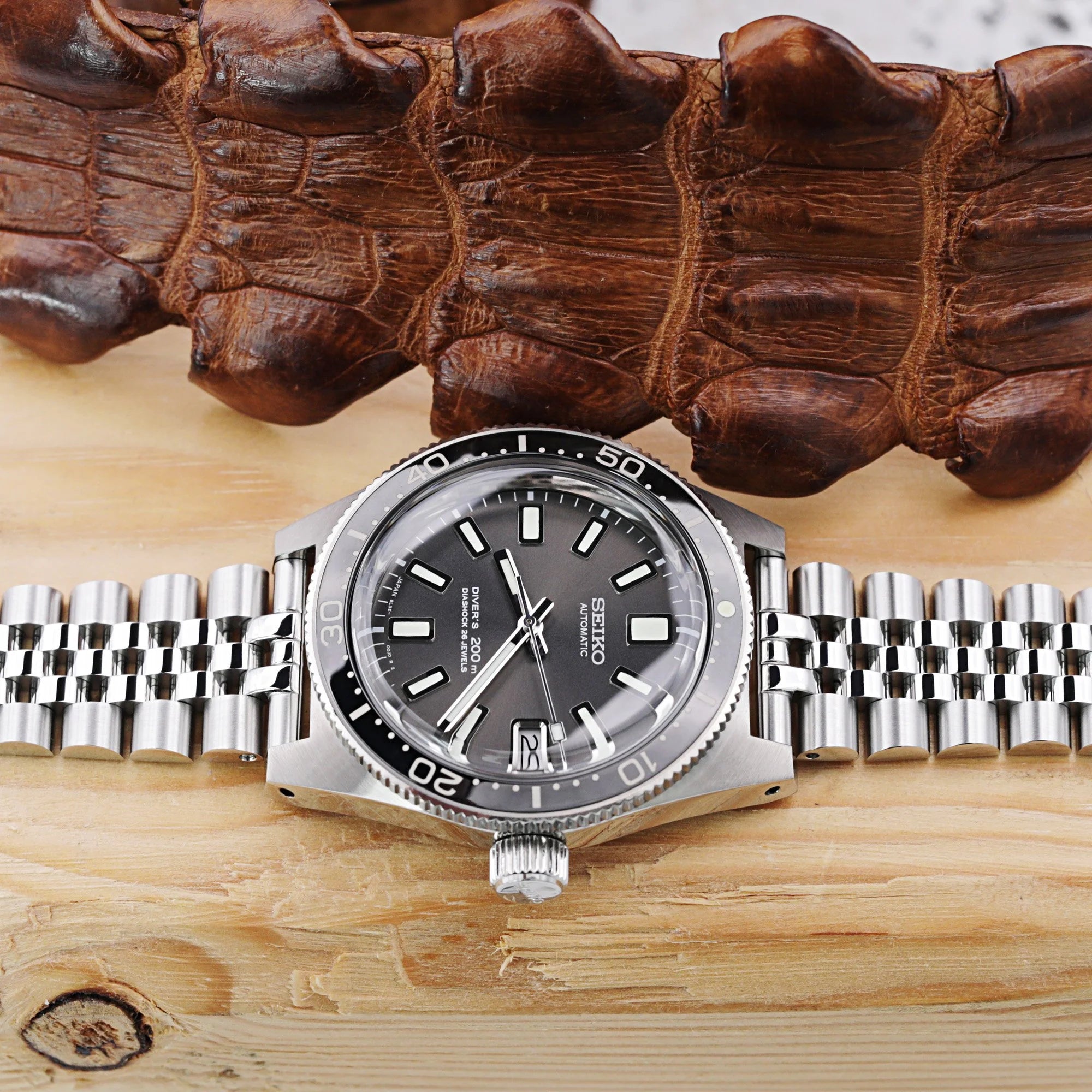 Strapcode Super-Jub II steel bracelet with V-clasp on automatic dive watch with dark dial and metal band