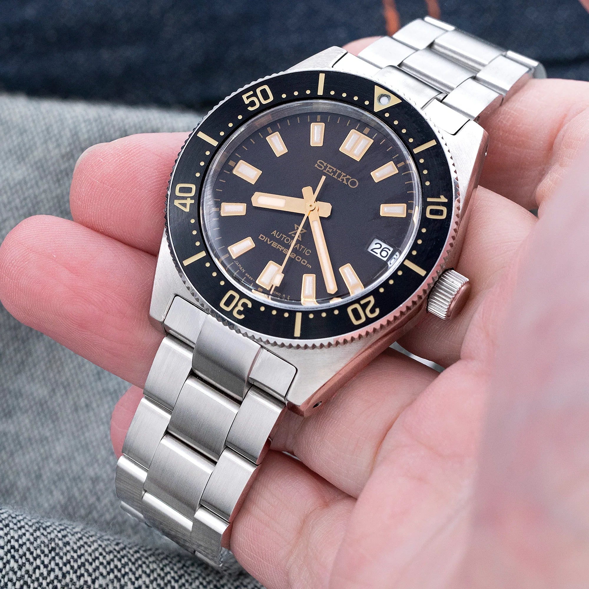 Seiko SPB143 63MAS automatic dive watch with black dial and gold indices on stainless steel Super-O Boyer bracelet, held in hand