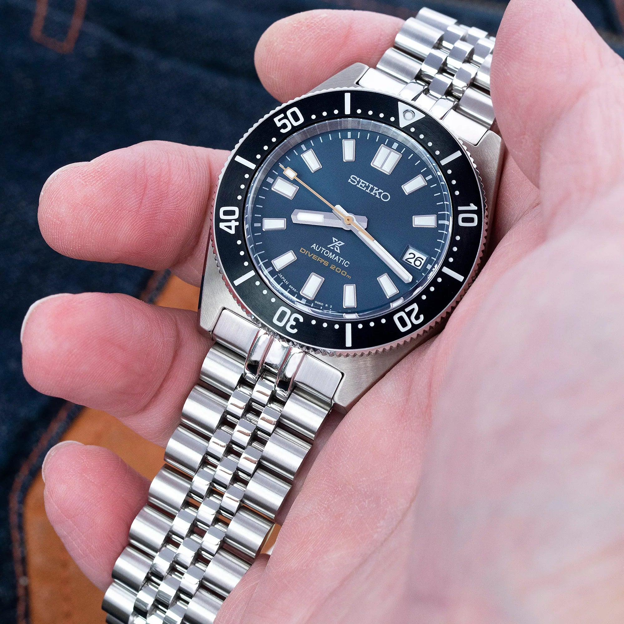 Seiko SPB143 63MAS dive watch with Super-J Louis stainless steel bracelet held in hand, featuring blue dial and black bezel