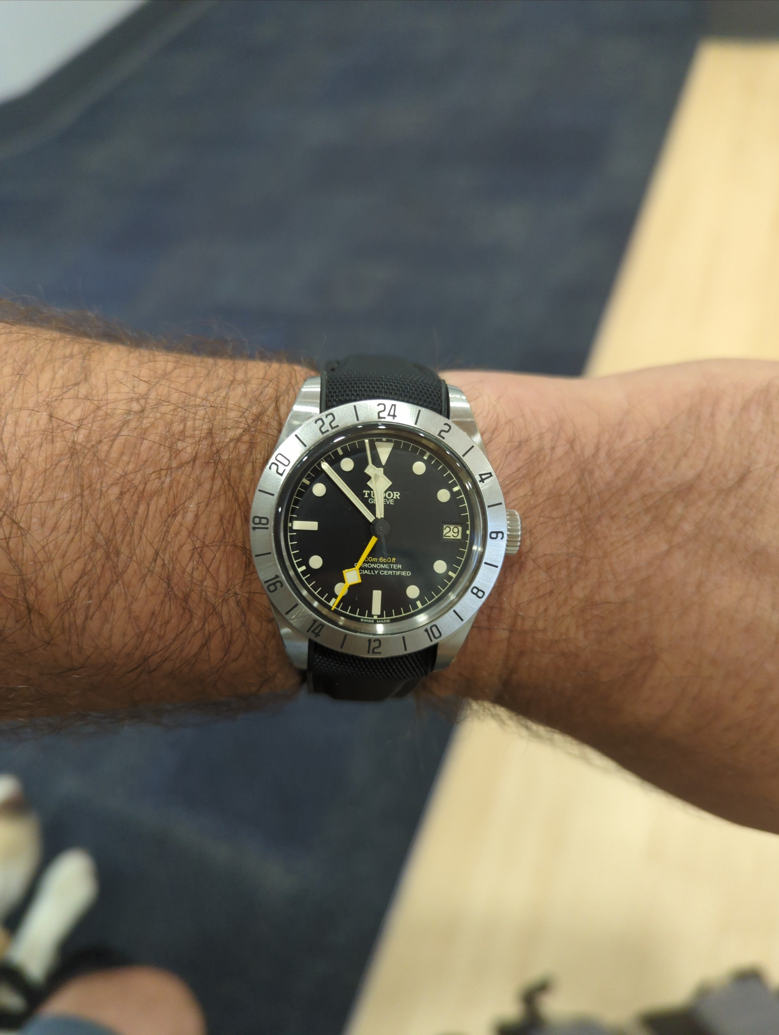 Tudor Black Bay steel dive watch with black dial, yellow hand, date window, and black rubber strap on wrist