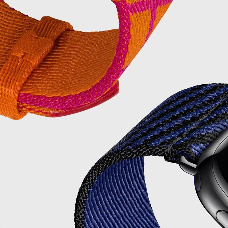 Colorful Apple Watch Single Tour bands in orange, pink, and blue woven nylon straps displayed on smartwatch