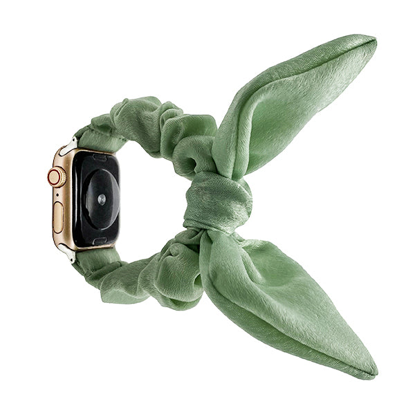 Gold smartwatch with sage green fabric scrunchie loop band featuring elongated ribbon tails