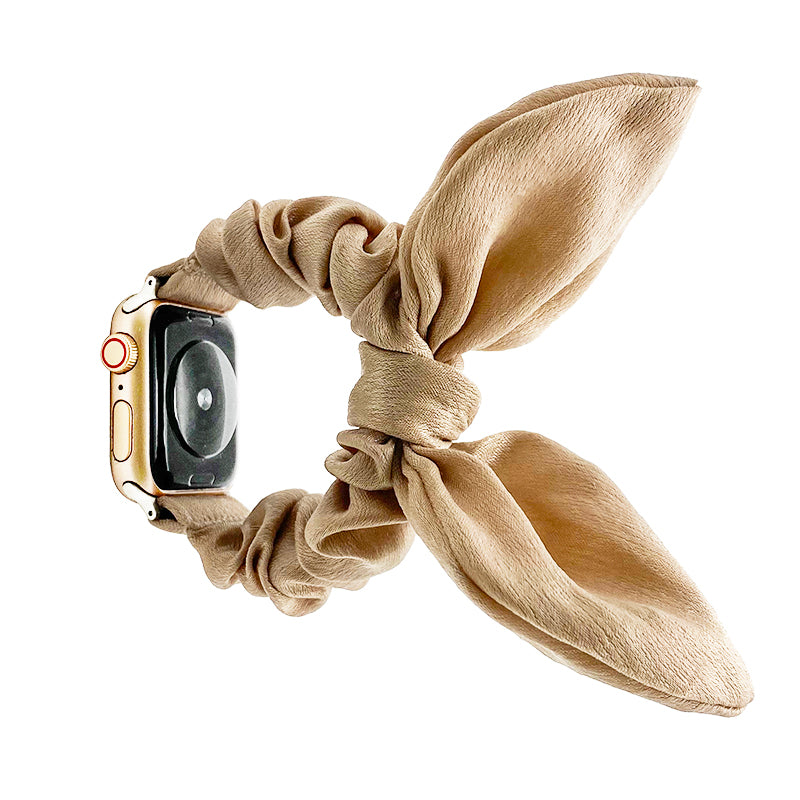 Beige fabric ribbon loop scrunchie smartwatch band with gold hardware connector on Apple Watch with black digital display