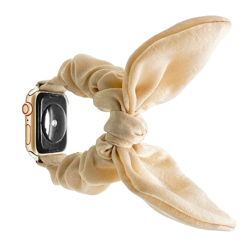 Cream silk ribbon scarf watch band for Apple Watch with gold case and black dial against white background