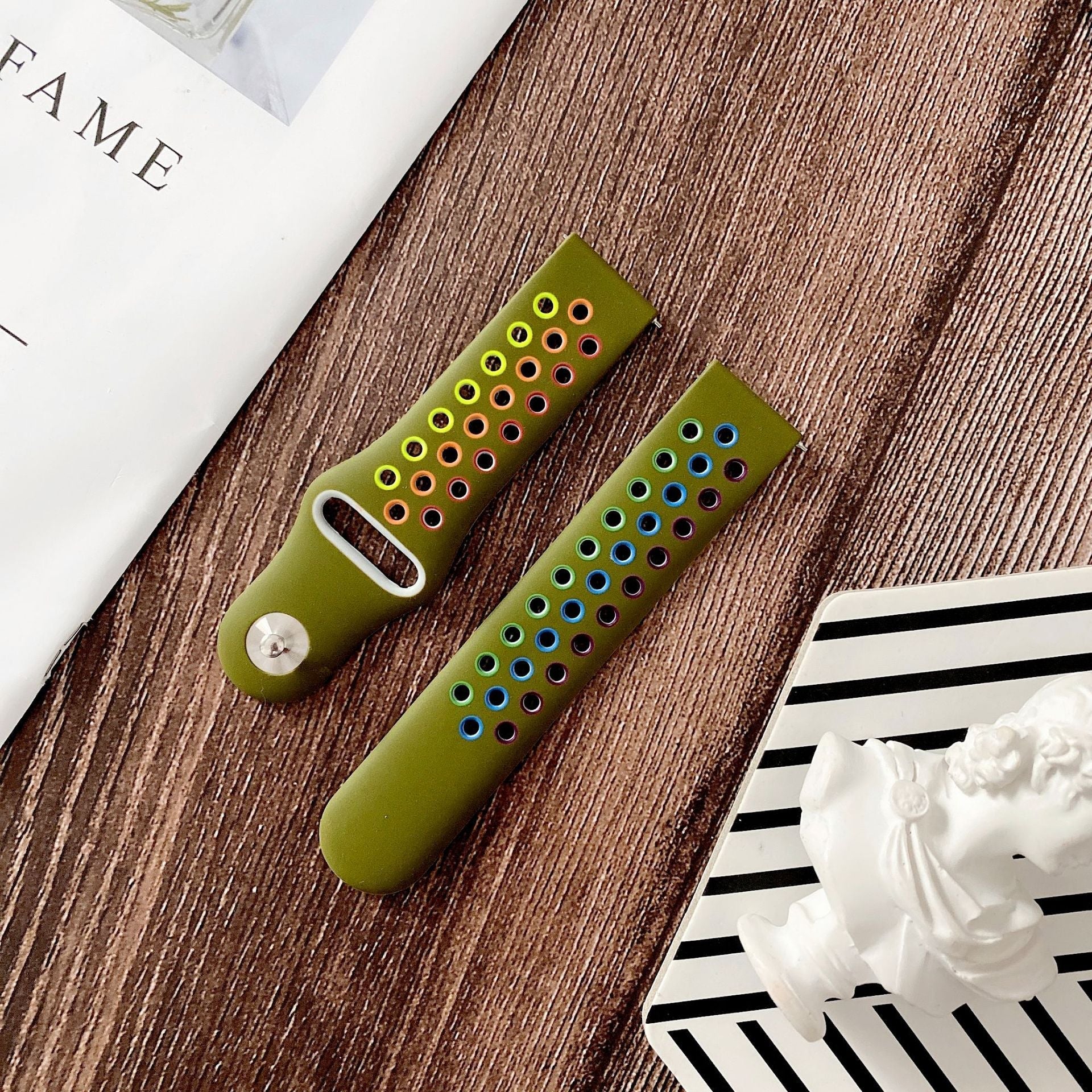 Olive green silicone sports watch band with colorful perforated holes and quick release mechanism displayed on wood surface