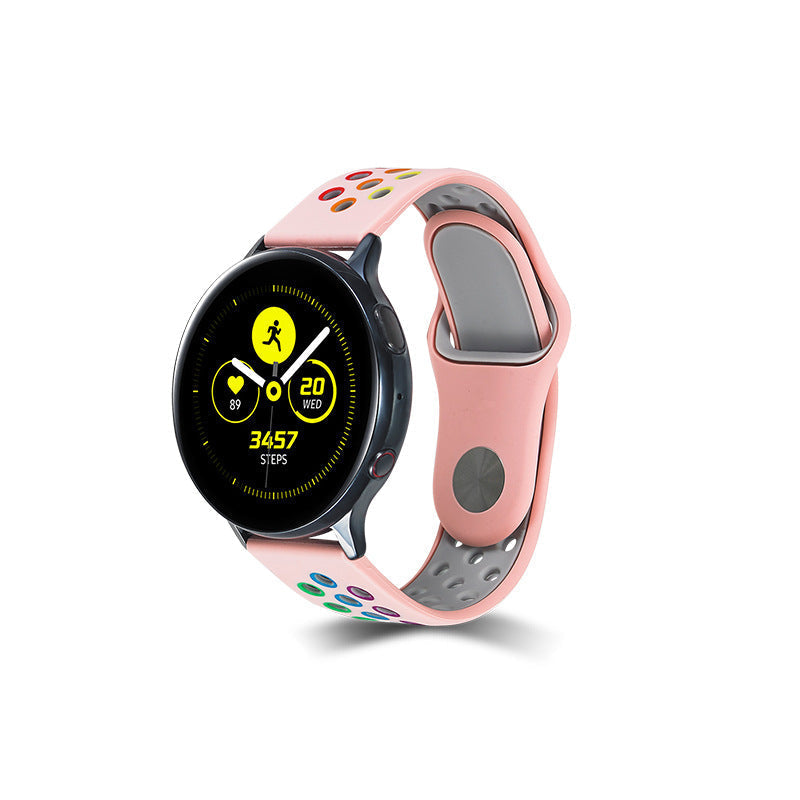 Pink silicone sports watch band with rainbow quick release dots, compatible with round smartwatch faces, featuring gray ventilation holes