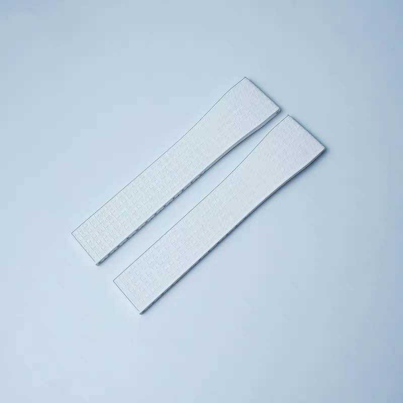 Two white textured rubber watch straps with leaf-spring deployant clasps arranged diagonally on light background