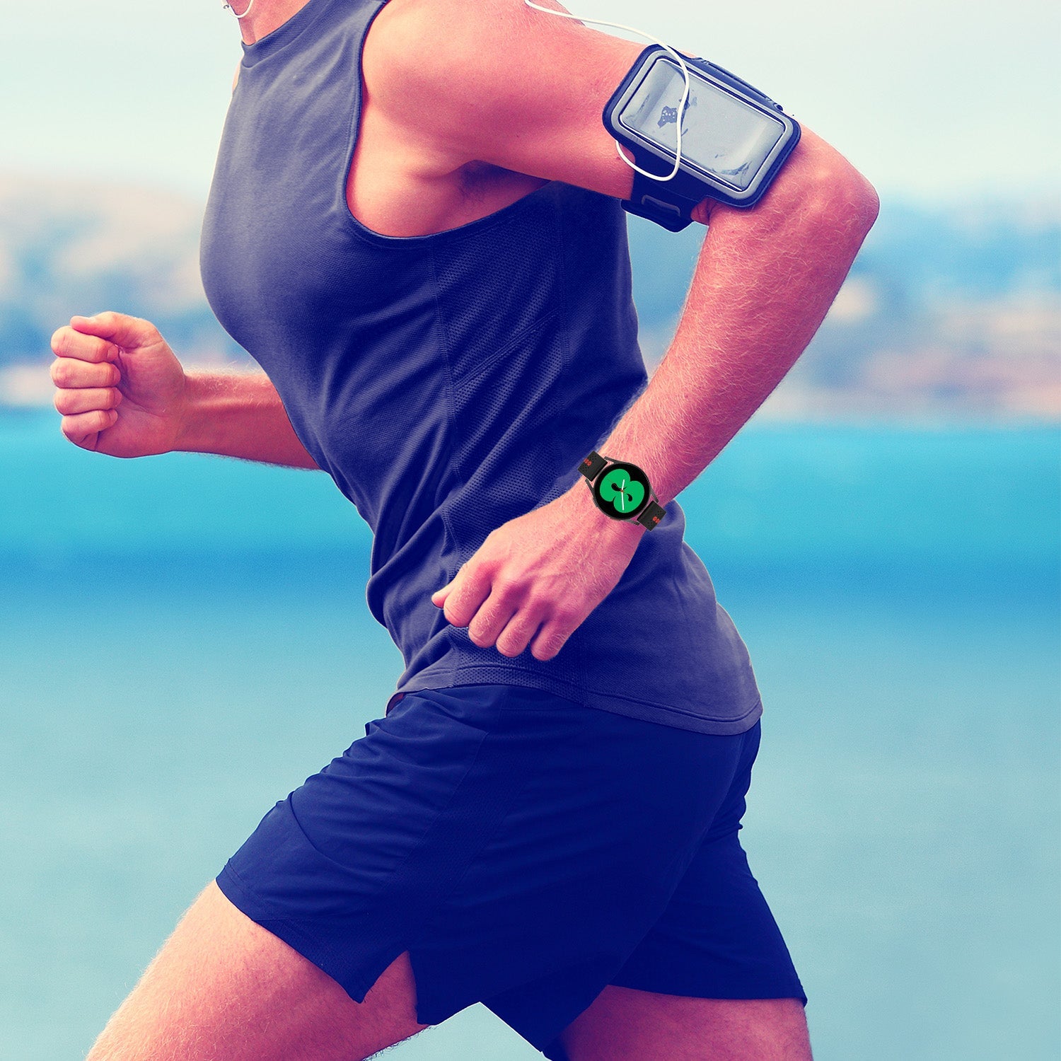 Runner wearing black sports tank top and shorts with smartwatch and phone armband by ocean coastline