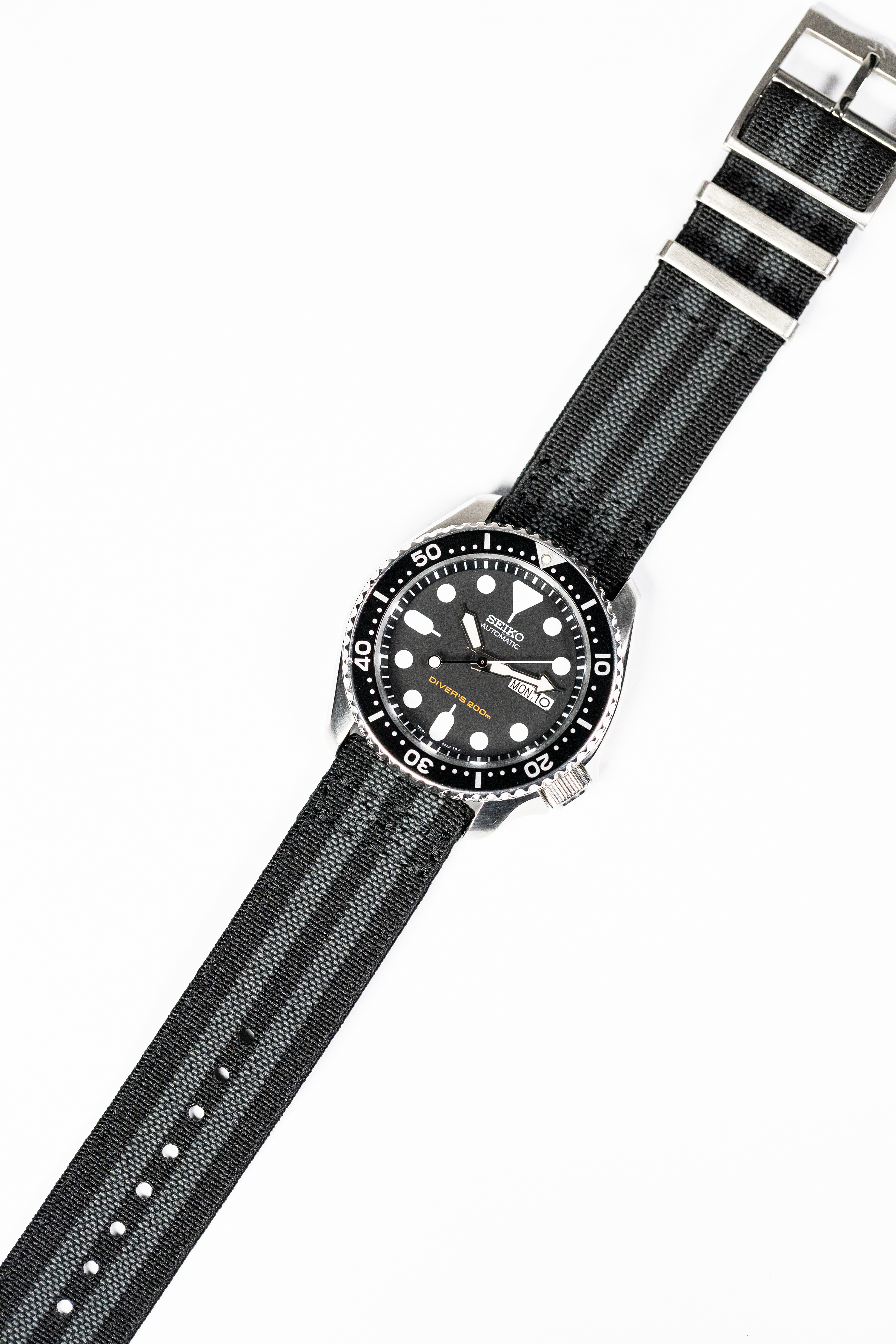Black Seiko automatic dive watch with striped elastic fabric quick-release strap and rotating bezel
