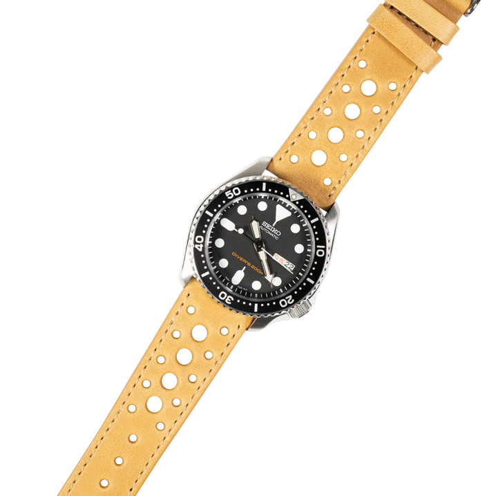 Dive watch with black dial and rotating bezel on tan perforated leather quick release strap