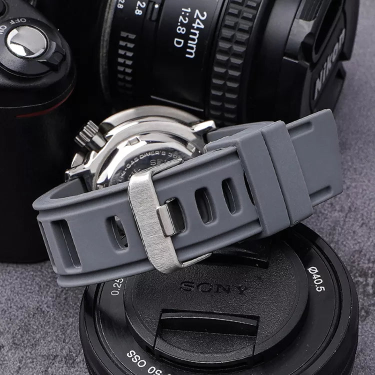 Gray silicone quick-release watch strap with metal buckle displayed on vintage camera lenses