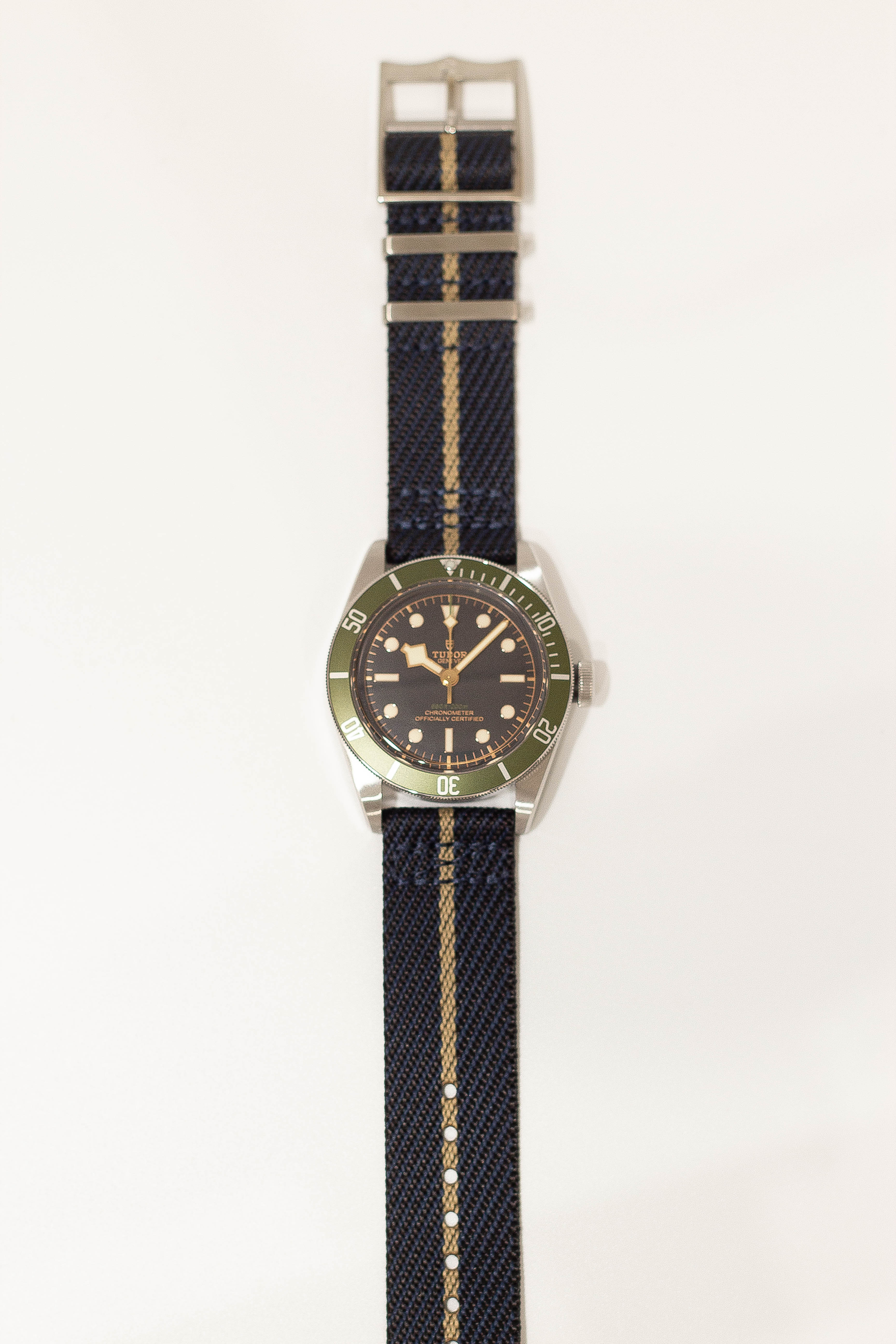 Stainless steel dive watch on dark blue fabric strap with wheat-colored stripe