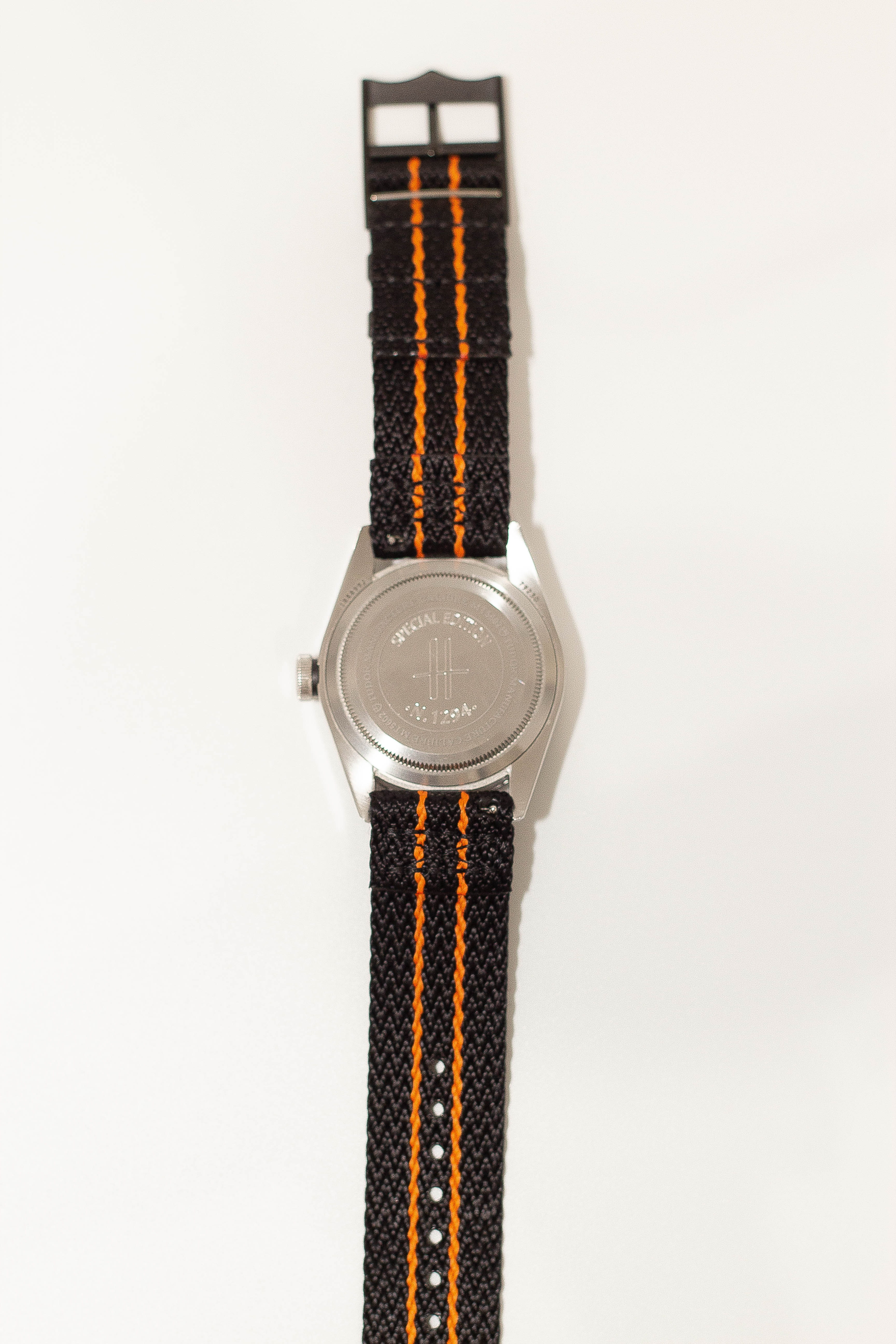 Stainless steel watch with black and orange striped military fabric quick release strap and black hardware