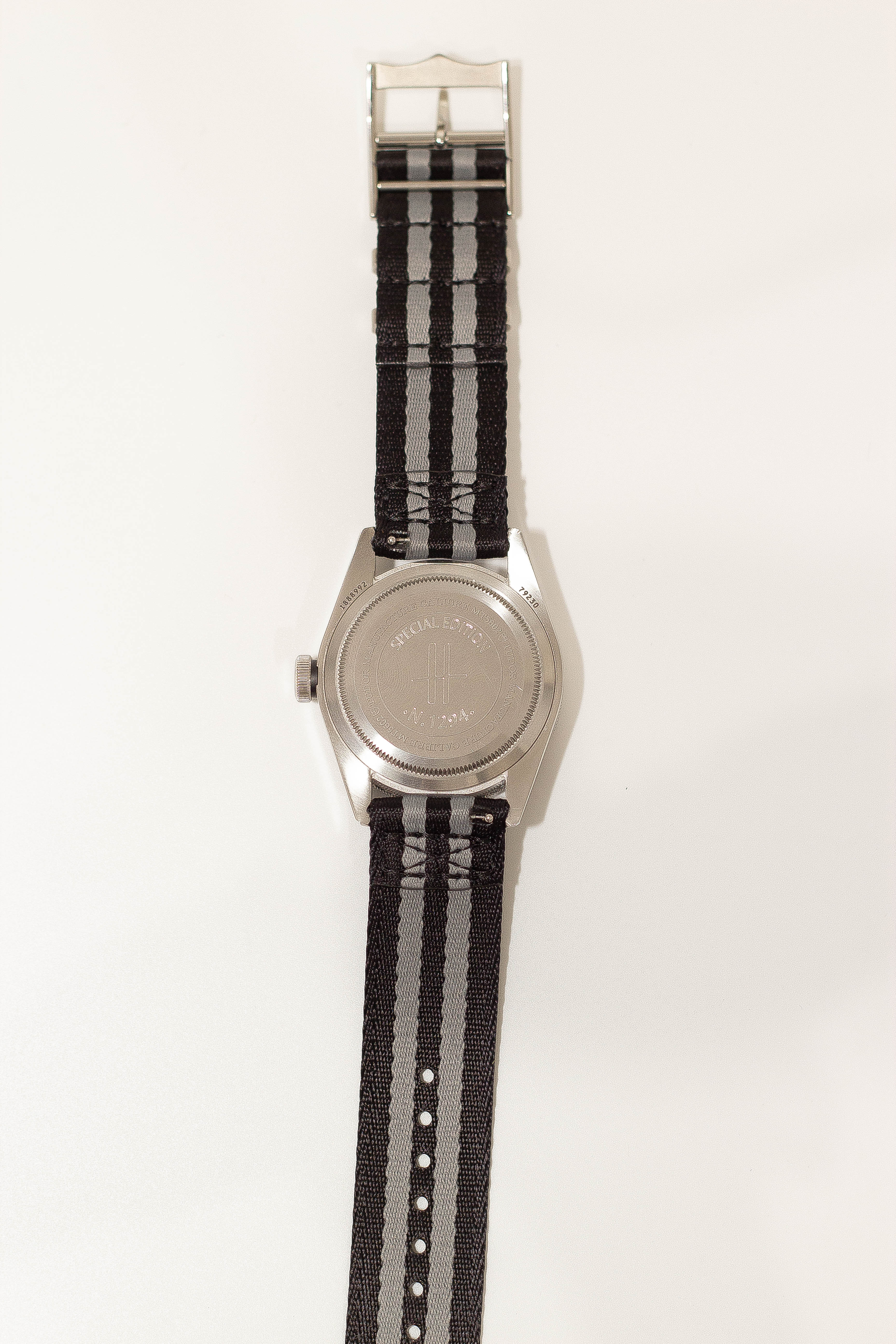 Stainless steel watch with black and grey striped fabric strap and quick release buckle, military-style timepiece