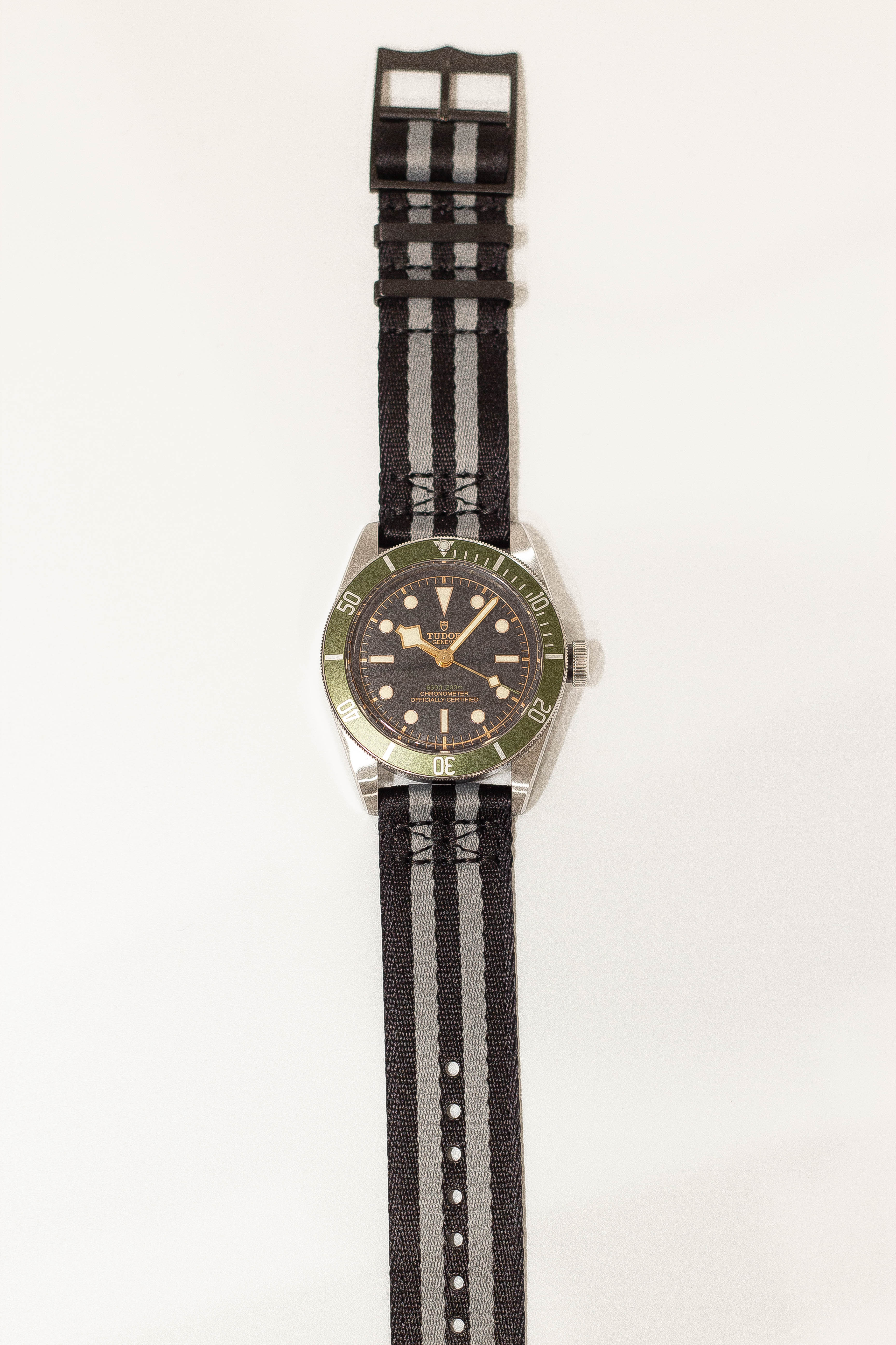 Tudor Black Bay dive watch on black and grey striped fabric strap with black hardware