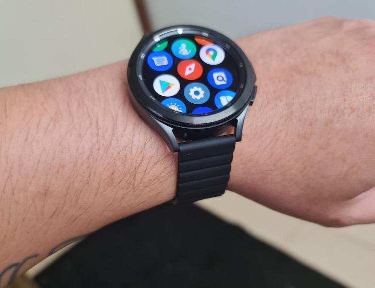 Black smartwatch with magnetic silicone loop band displaying colorful app icons on AMOLED screen