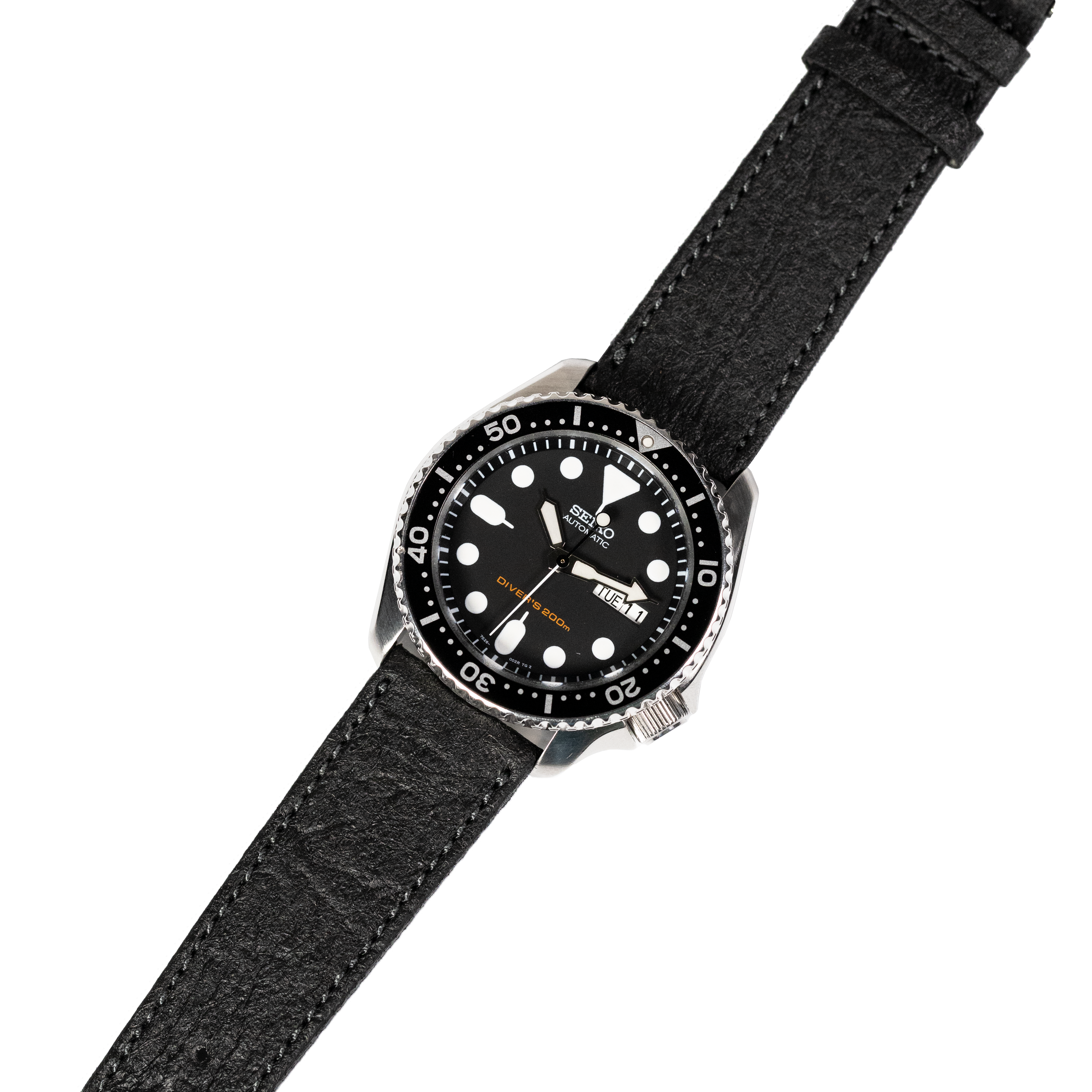 Seiko dive watch with black dial, luminous markers, and rotating bezel on black vegan leather quick-release strap