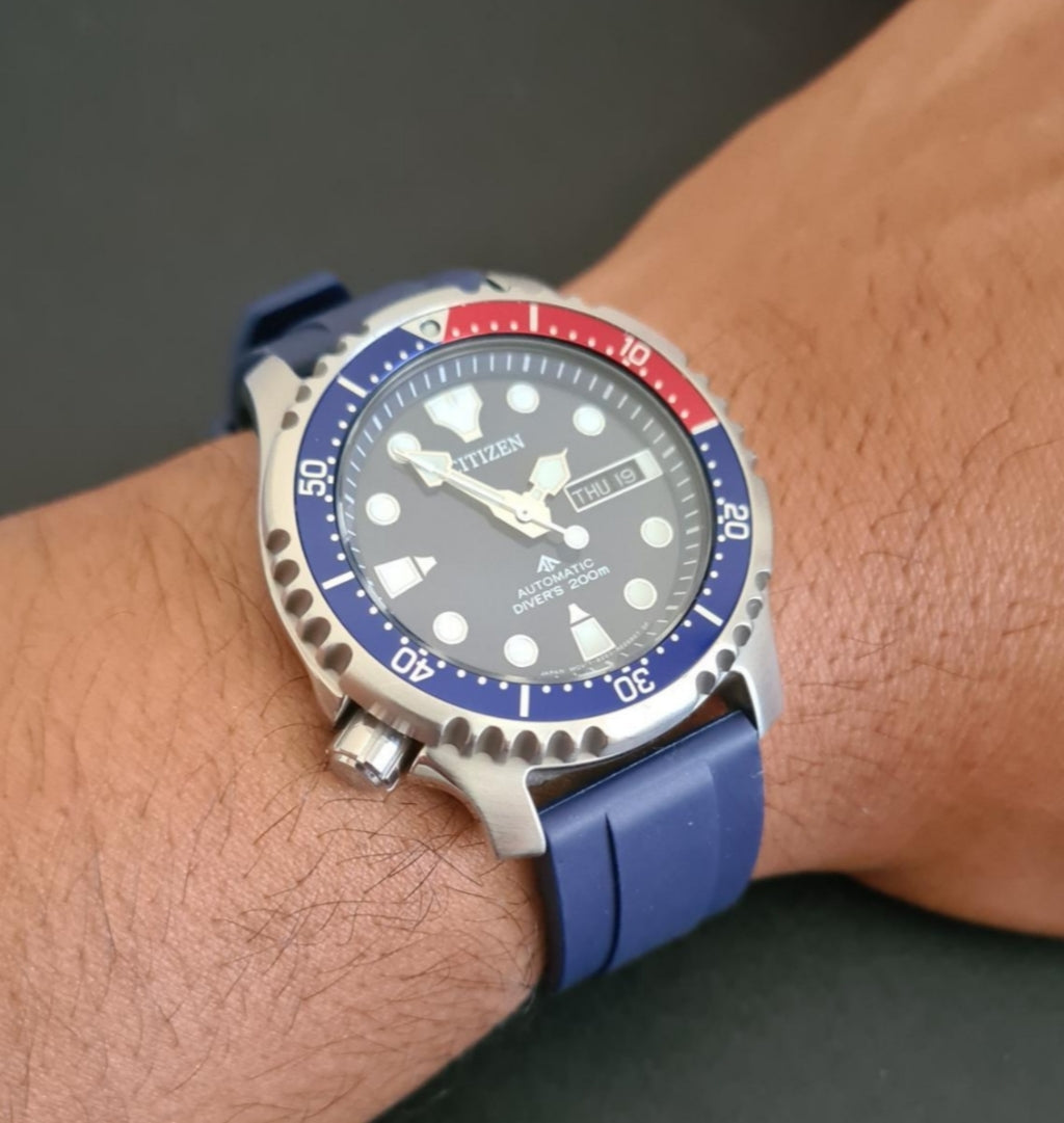 Citizen automatic dive watch with blue red bezel rubber strap on wrist showing day date window