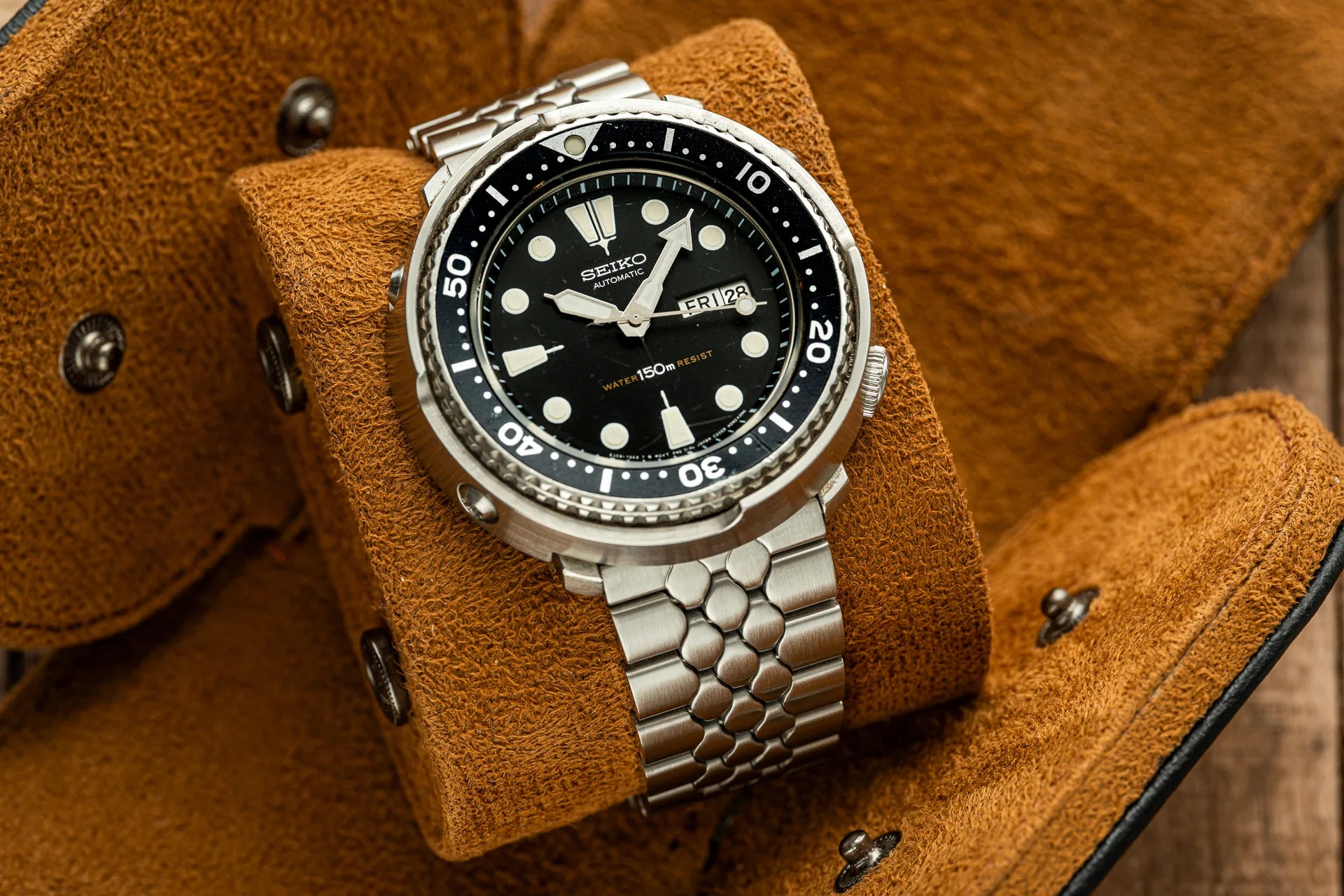 Seiko automatic dive watch with black dial, white hour markers, stainless steel bracelet on tan leather cuff
