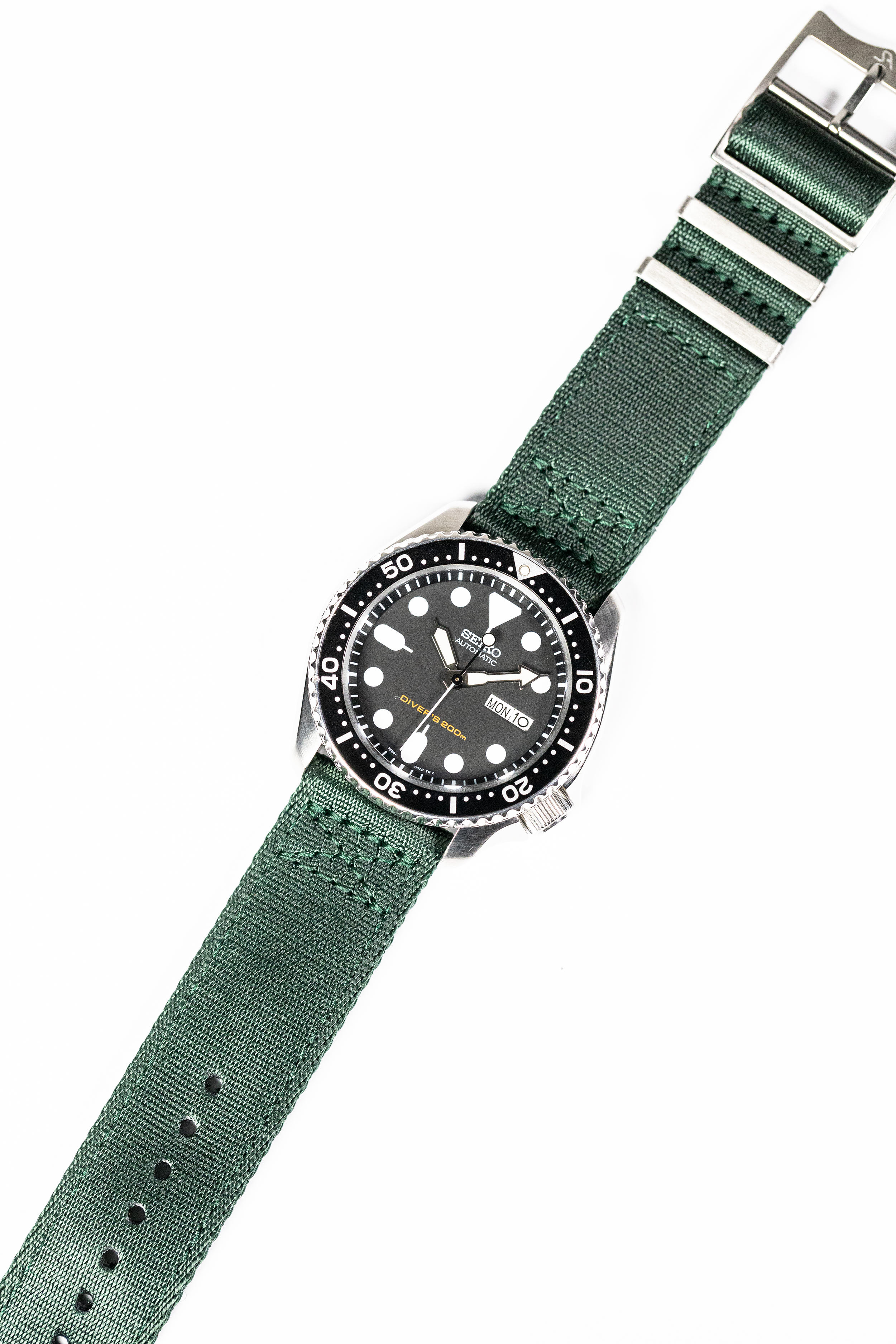Seiko dive watch with black dial and rotating bezel on forest green fabric military-style strap with metal buckle