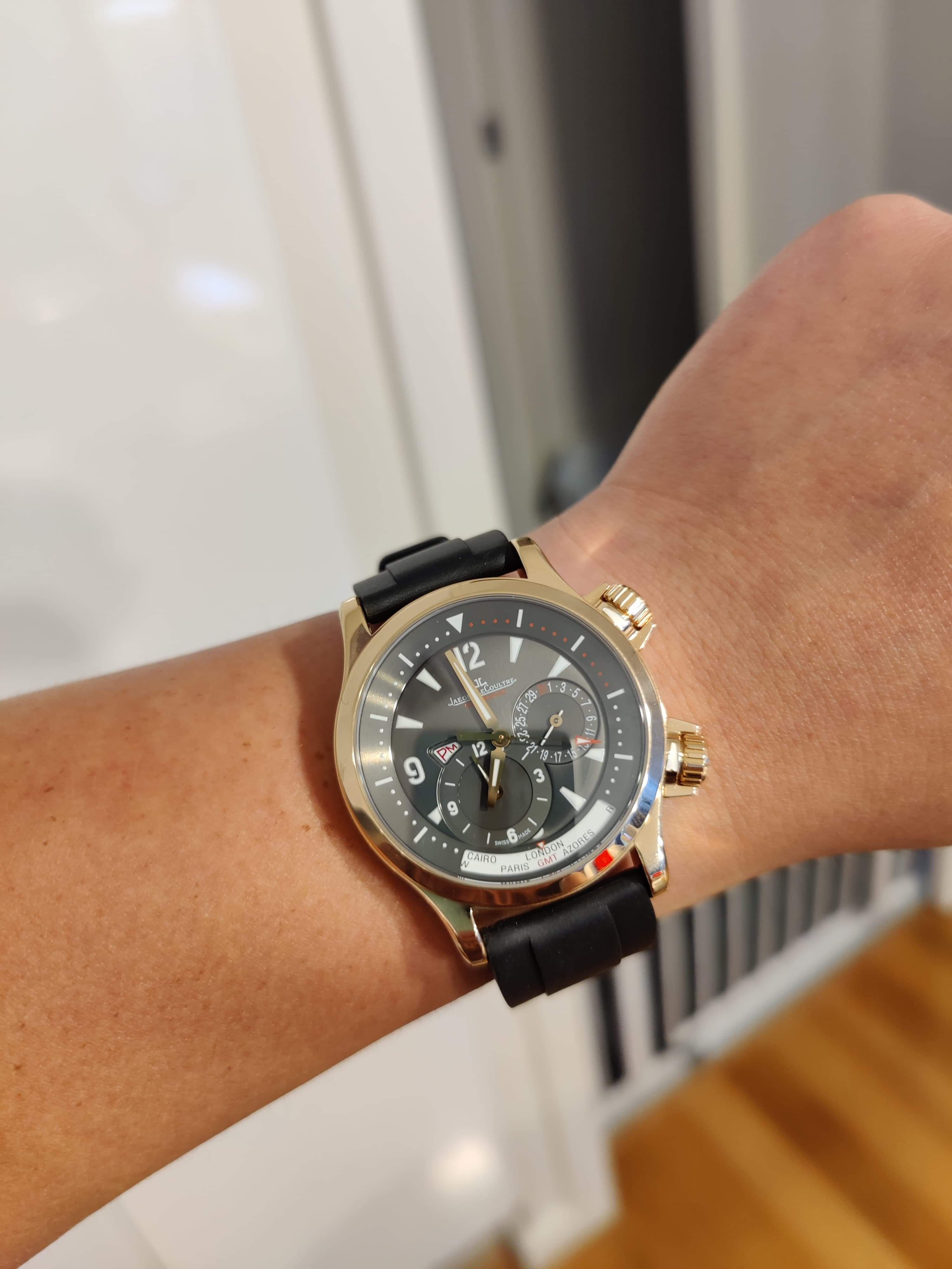 Gold and black chronograph watch with black rubber quick release strap worn on wrist